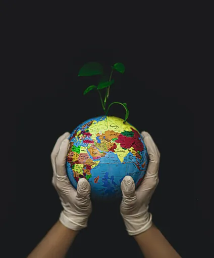 Manos sosteniendo un globo terráqueo con una planta
